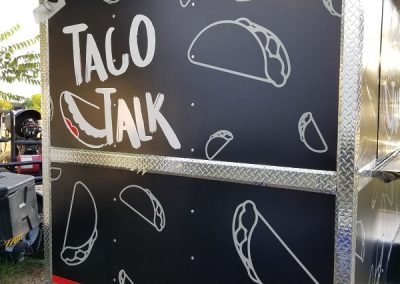Rear view of a food Vehicle Wrap with Taco Talk logo and stylized taco figures.